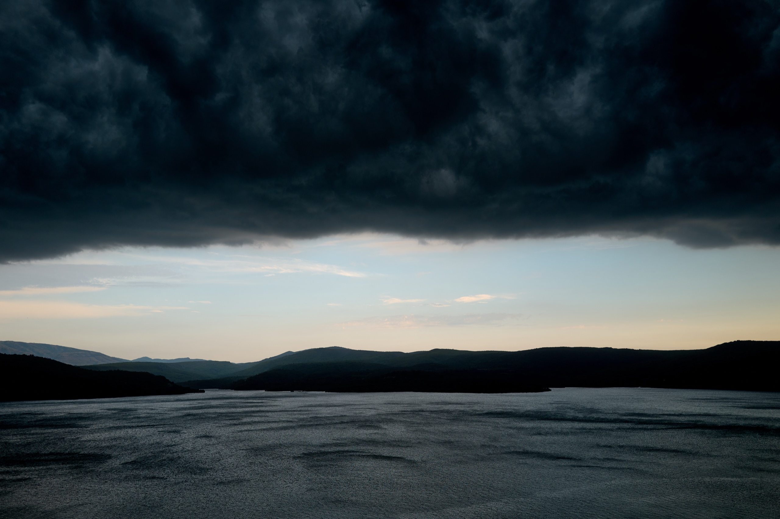 Storm clouds gathering over a lake at dusk — photograph by Stephan Borowski